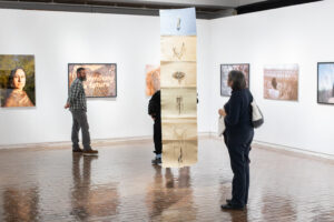 three attendess of an art exhibtion looking at the work