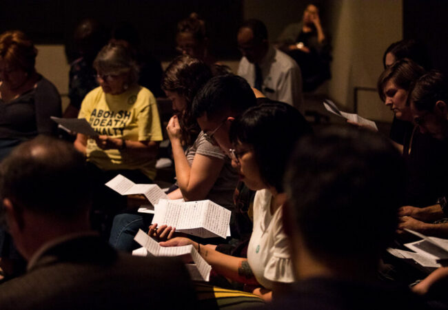 A woman surrouned by group reading a letter